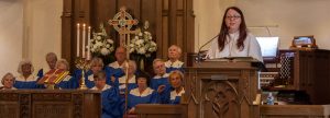 woman speaking at church with choir behind her